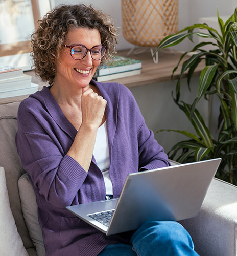 Mature woman using laptop while relaxing sitting on the couch at home